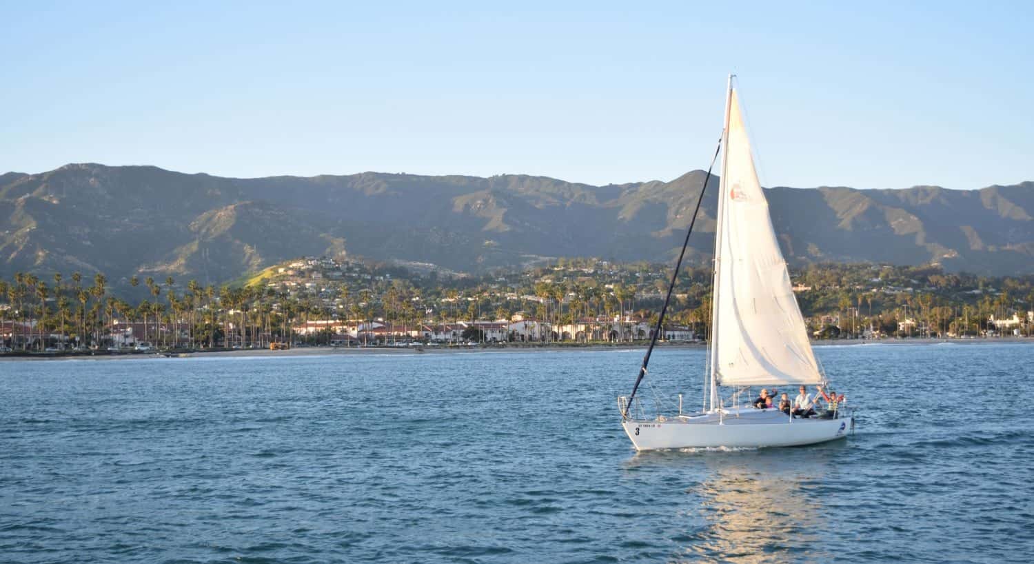 Sailboat sailing in the water with Santa Barbara and mountains in the background