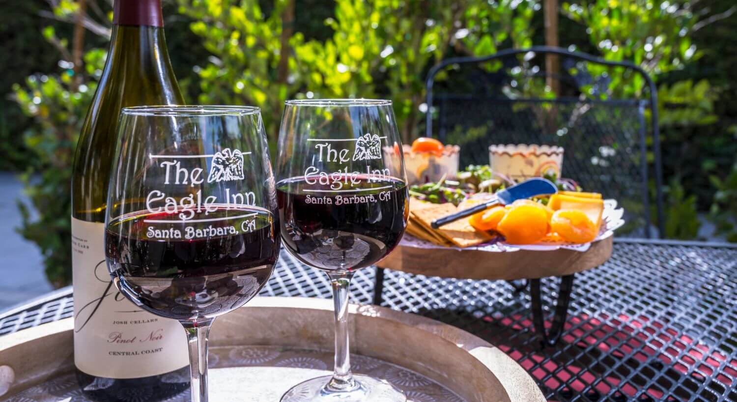 charcuterie board, 2 wine glasses with the eagle inn logo filled with red wine, Josh wine bottle on tray behind
