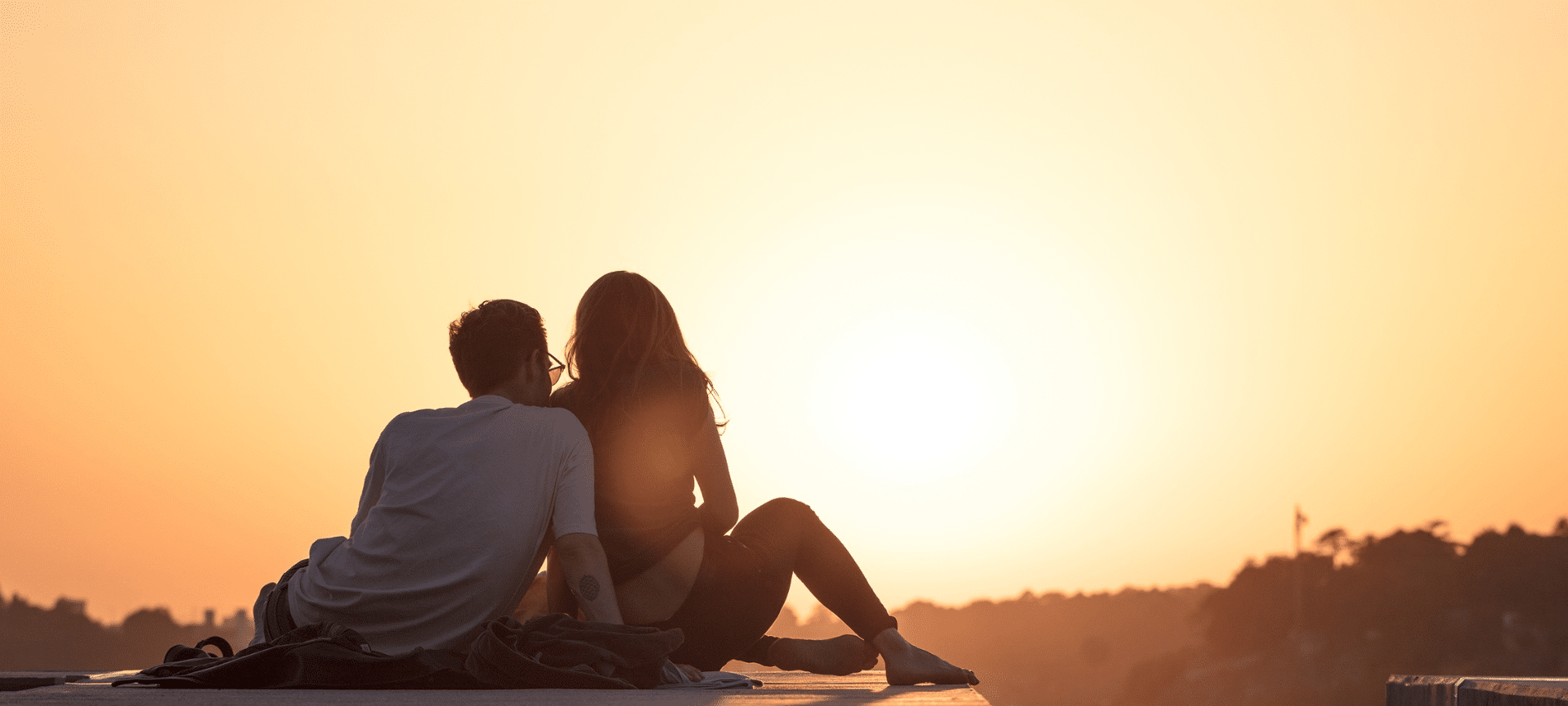 couple sitting close together watching the sunset 
