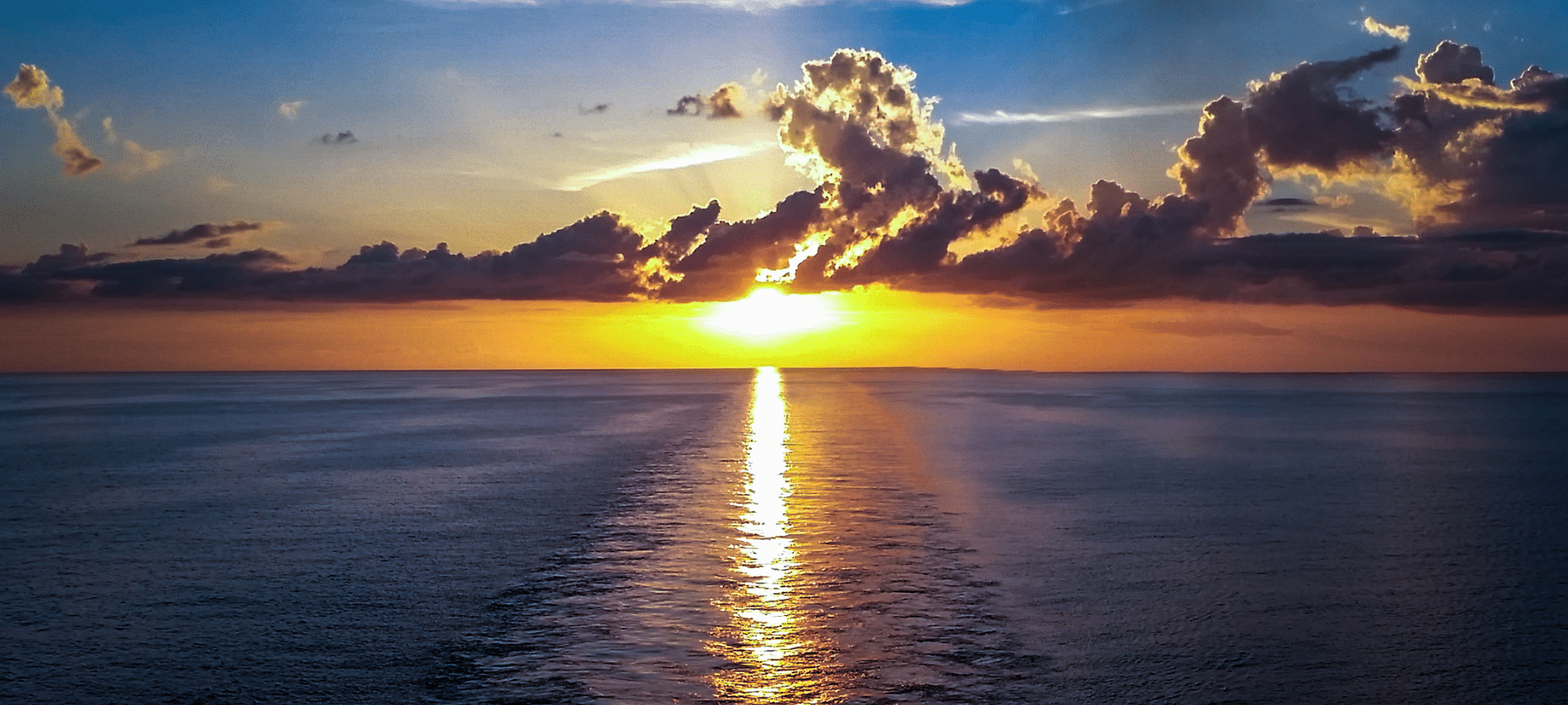 ocean sunset with sunlight reflecting across the water beneath clouds