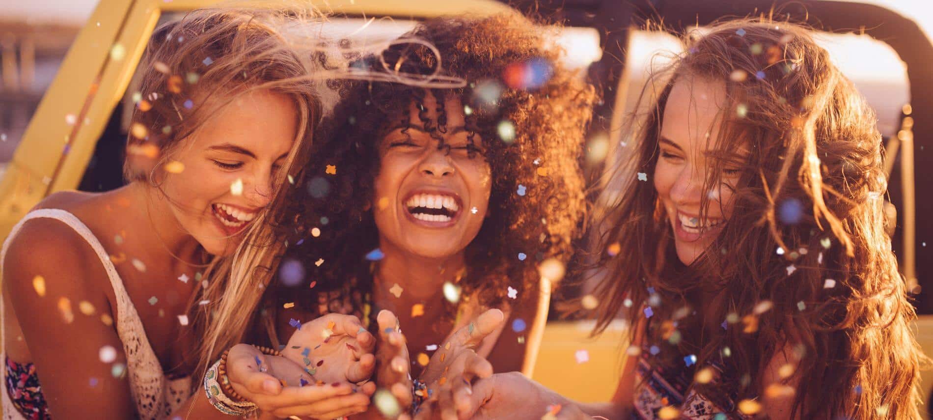 group of girls blowing confetti while on a girls trip
