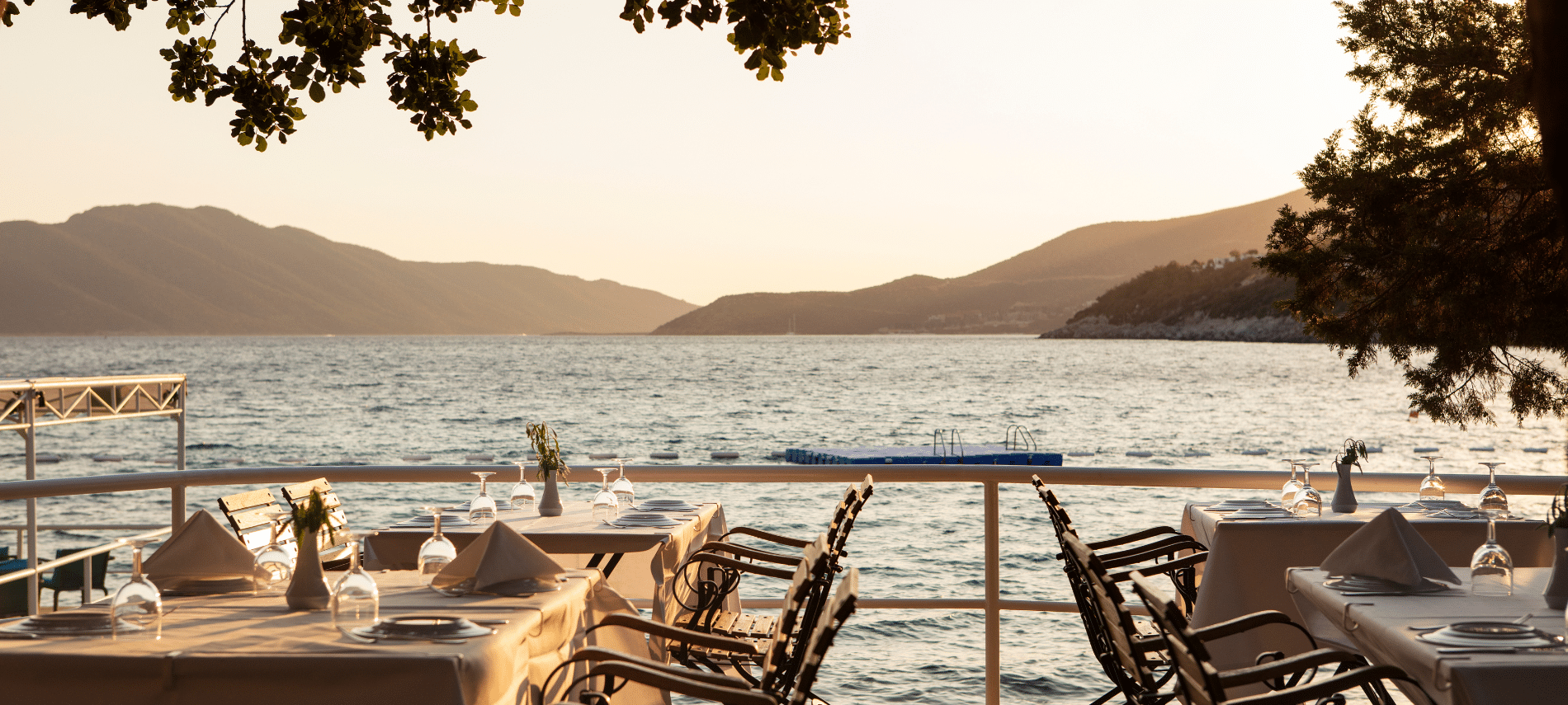 outdoor seaside restaurant with tables set for dining overlooking calm water 