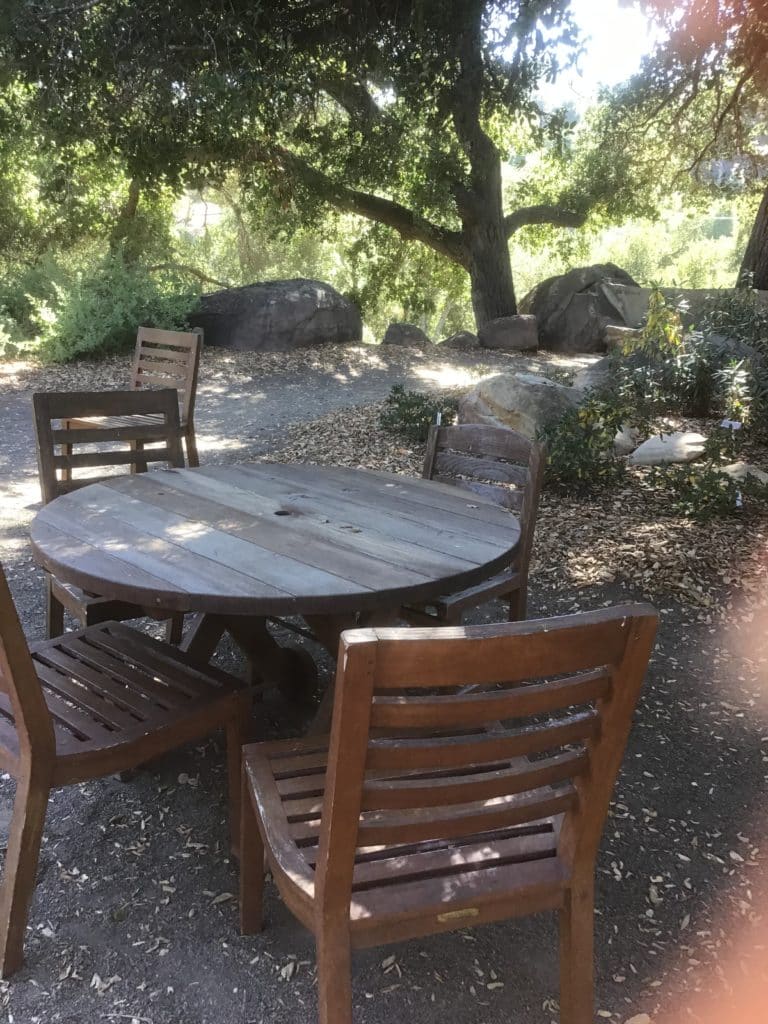 wooden chairs around a round wooden table, outdoors