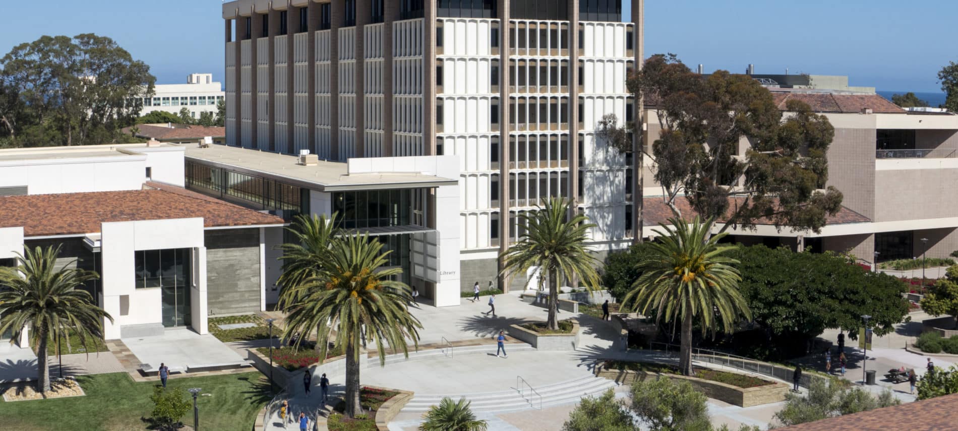 Exterior aerial view of University of California Santa Barbara Library amidst palm trees and blue skies