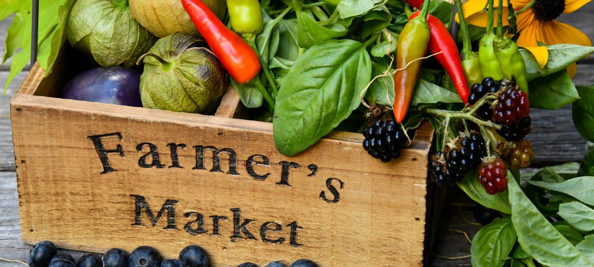 Wood basket engraved with "farmers market" filled with colorful produce