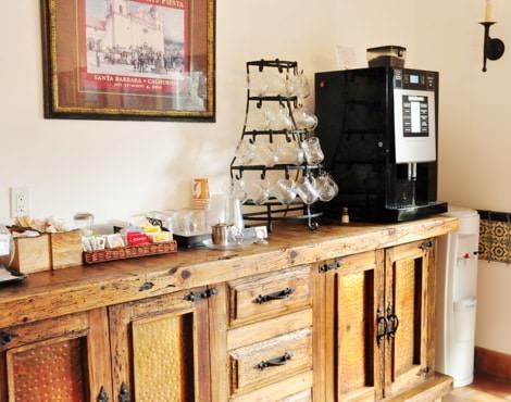 Guest beverage counter in rustic wood with coffee maker, glass mugs, and beverage supplies