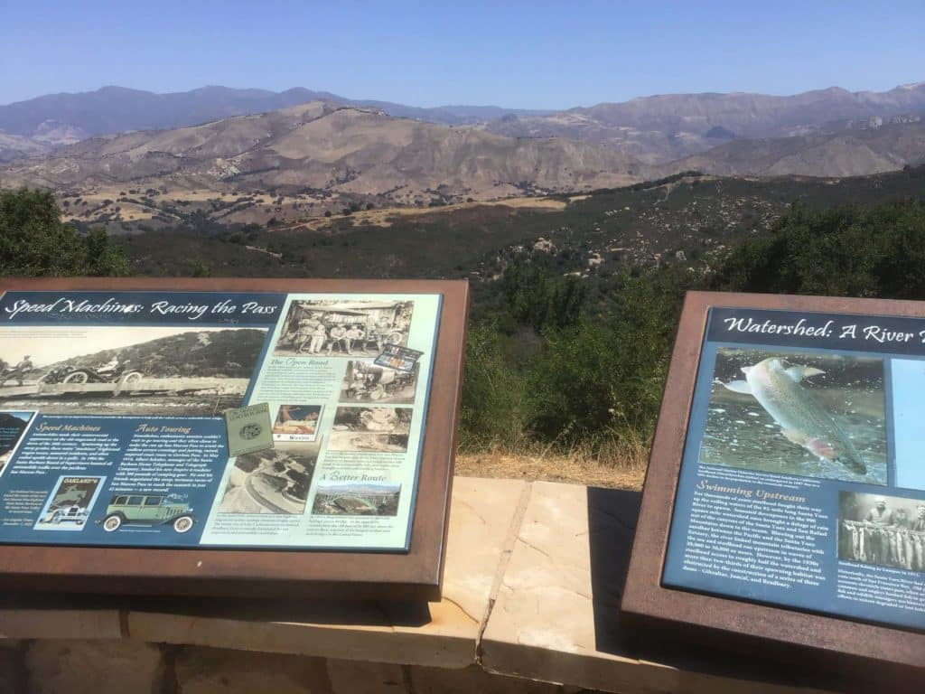 Information boards with historical pictures in front of roadside pullout mountains in the back