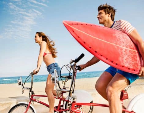 A man and woman riding bikes on a beach