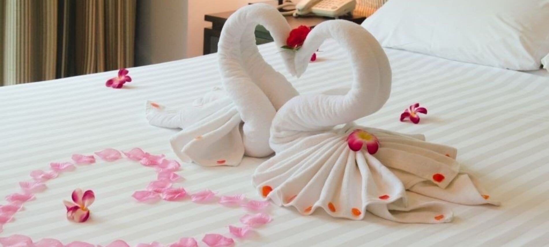 Swan towels and rose petal heart on a luxurious bed.