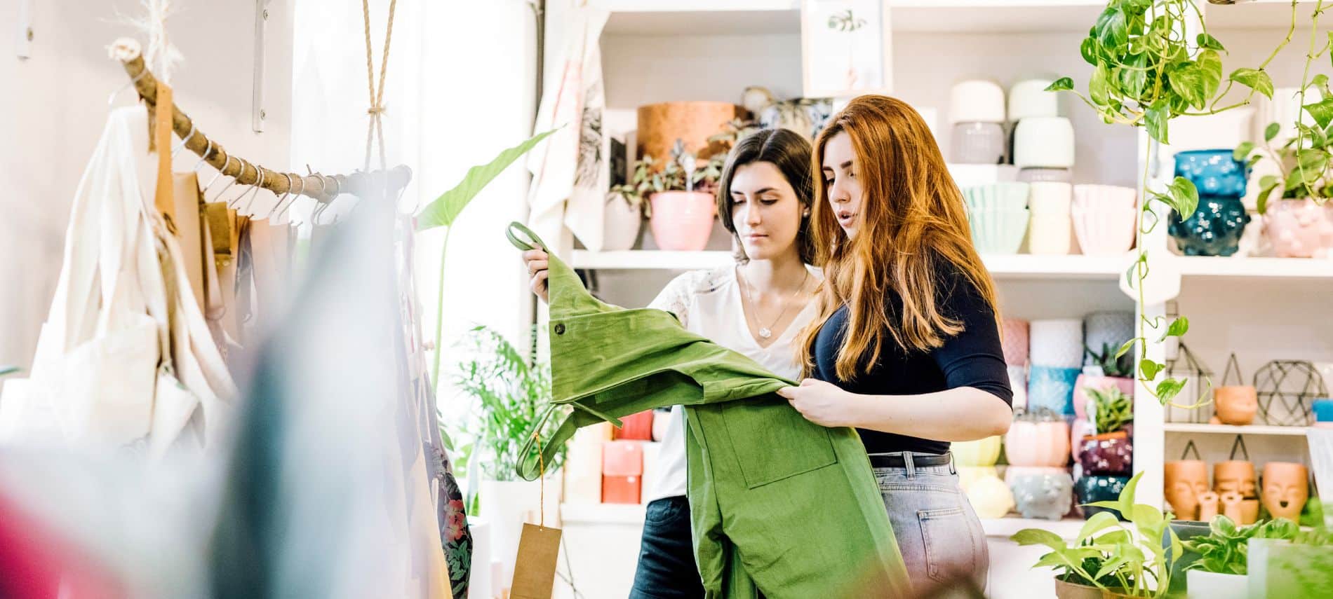 Two women are shopping in a fun boutique store that has plants