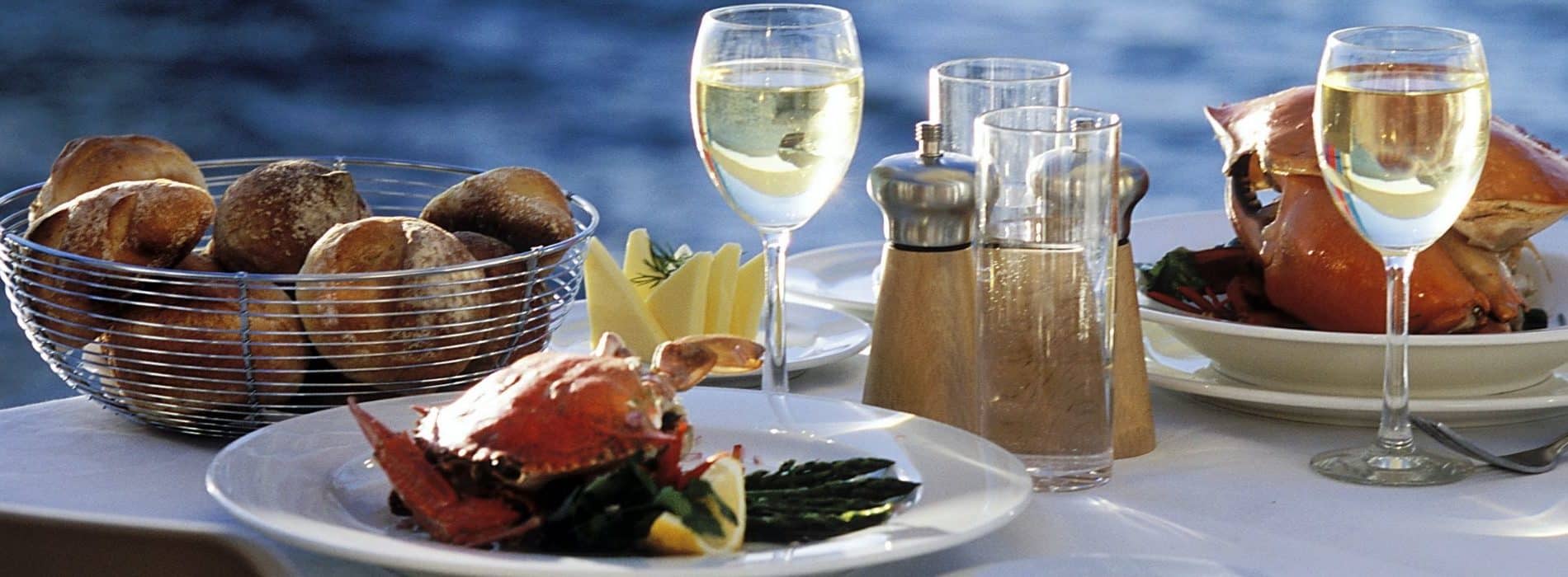 Dining table by the water set with seafood and white wine