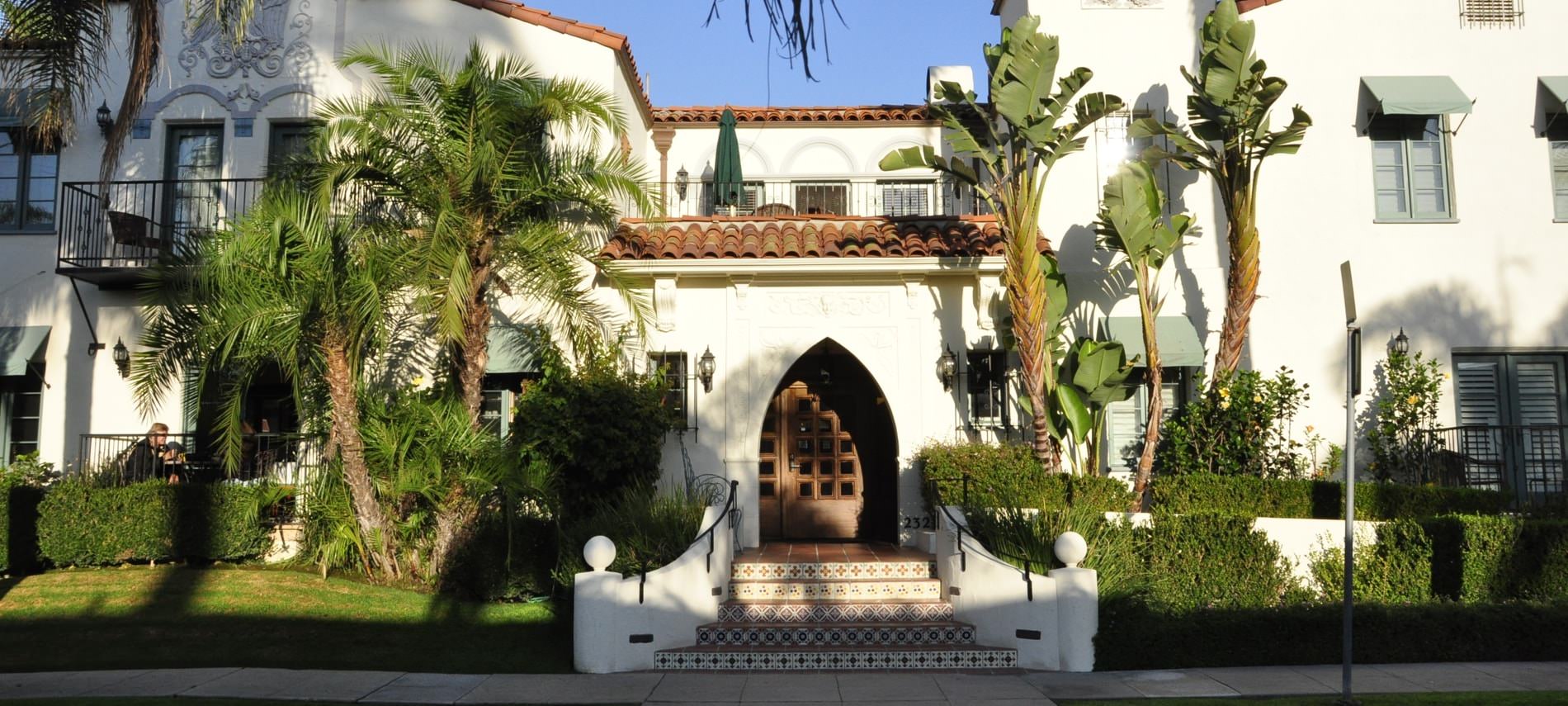 The Eagle Inn, white Spanish style building with red tiled roof, pointed arch opening, balconies and palm trees