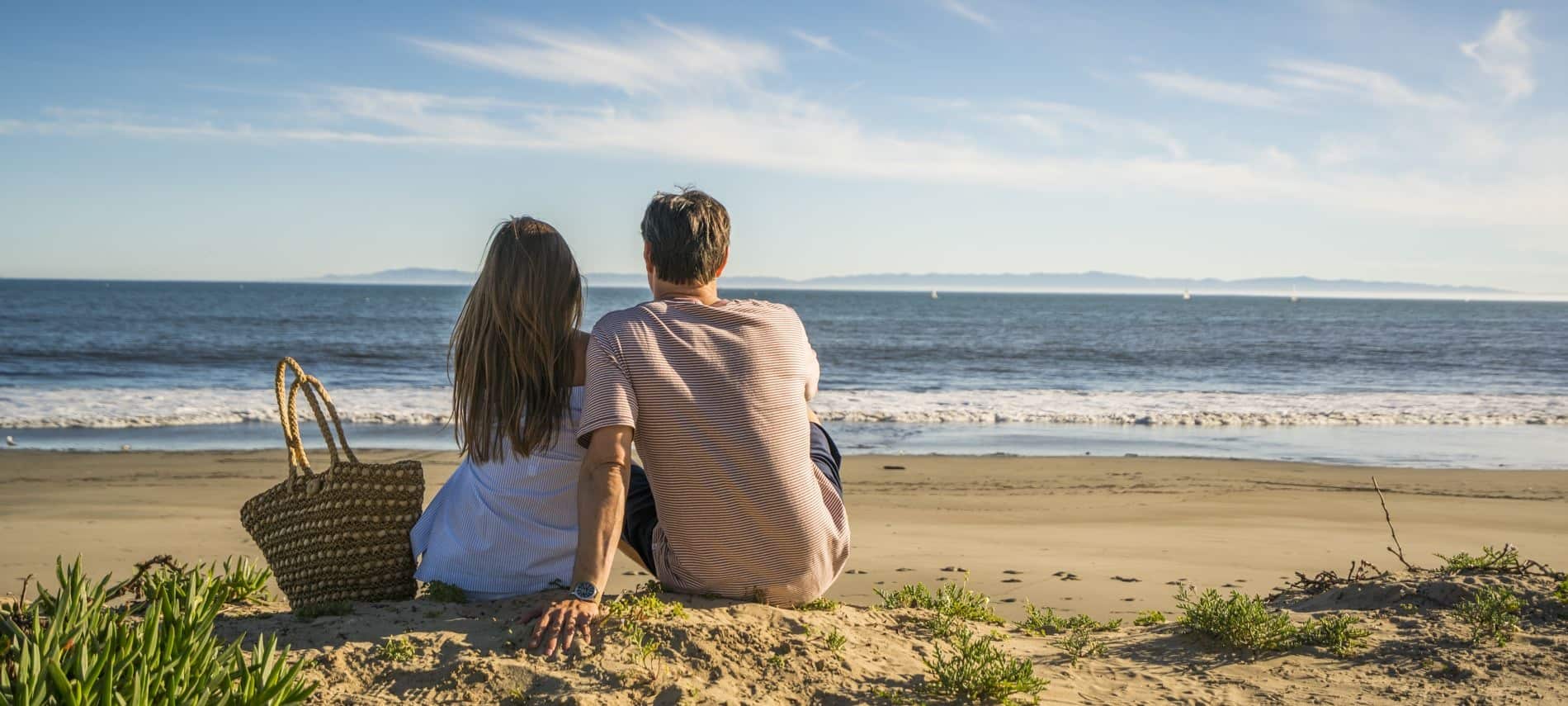 Man and woman sitting on the beach with a picnic basket