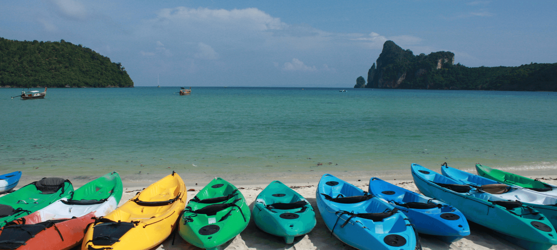 Kayaks lined up on beach on lakeshore.