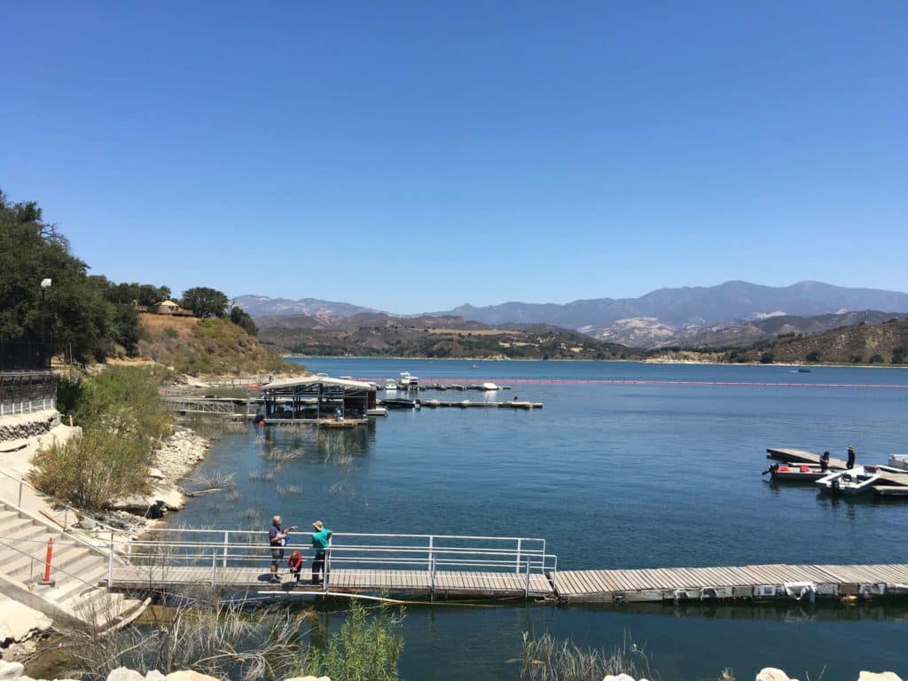 blue lake with a brown dock and grayish mountains in the background