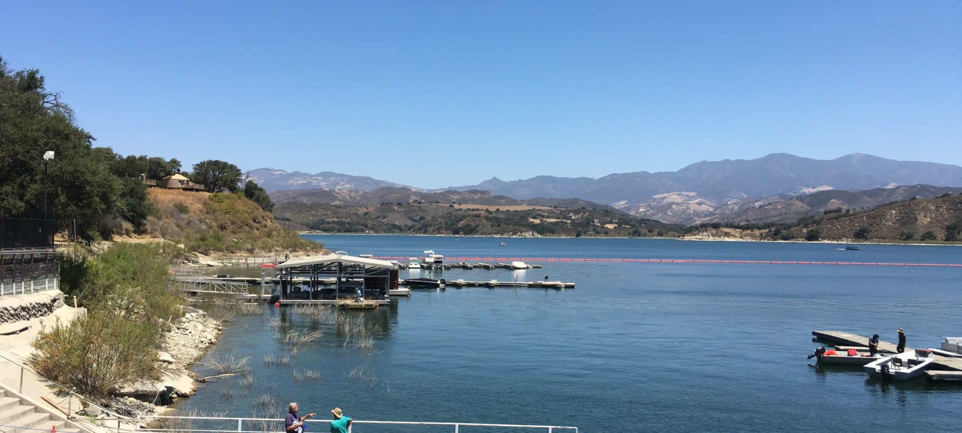 blue lake with a brown dock and grayish mountains in the background