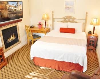 Anacapa guest room with bed, desk with chair, nightstand with lamp and fireplace