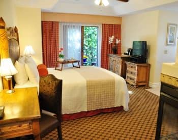 Deluxe king guest room with patio doors, desk with chair, carpeting, and television