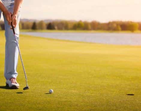 Man putting on a golf course with water nearby