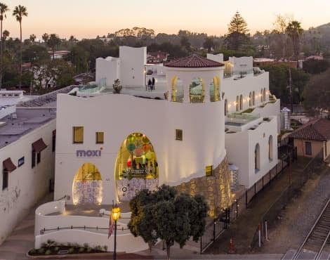 White Spanish-style MOXI museum surrounded by trees