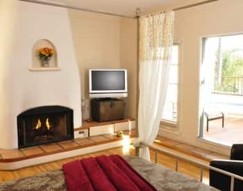 Queen balcony guest room with fireplace, television, and wood floors