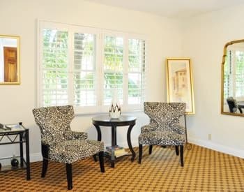 Santa Cruz guest room with ivory walls, carpeting, large window and two sitting chairs