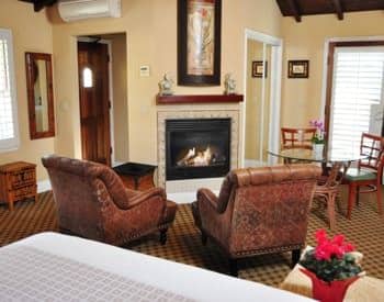 Spacious Santa Rosa guest room with fireplace, two leather chairs, and carpeting