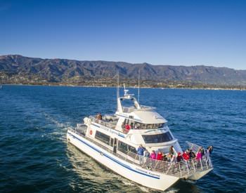 Cruise ship riding through the water with mountains in the background