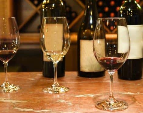 Three wine glasses and bottles on a table