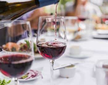 Two glasses of red wine on a table set for a meal