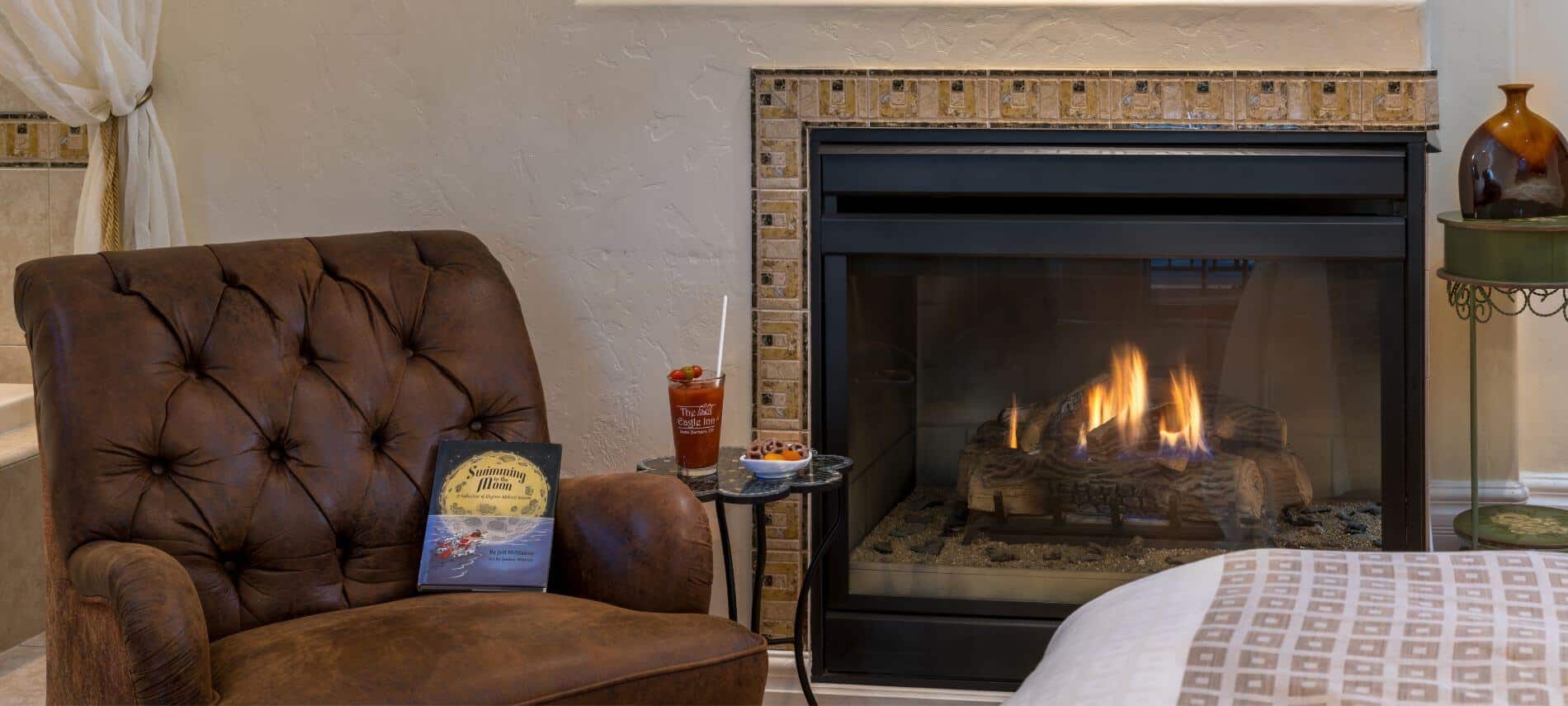 cream room with brown chair and book in corner, stand holding refreshments, fireplace