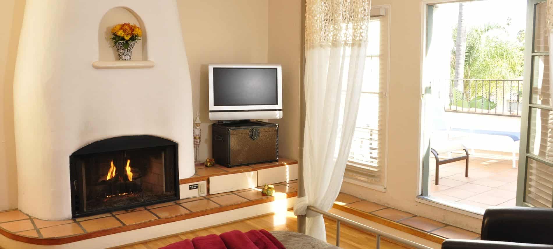 Queen balcony guest room with fireplace, television, and wood floors