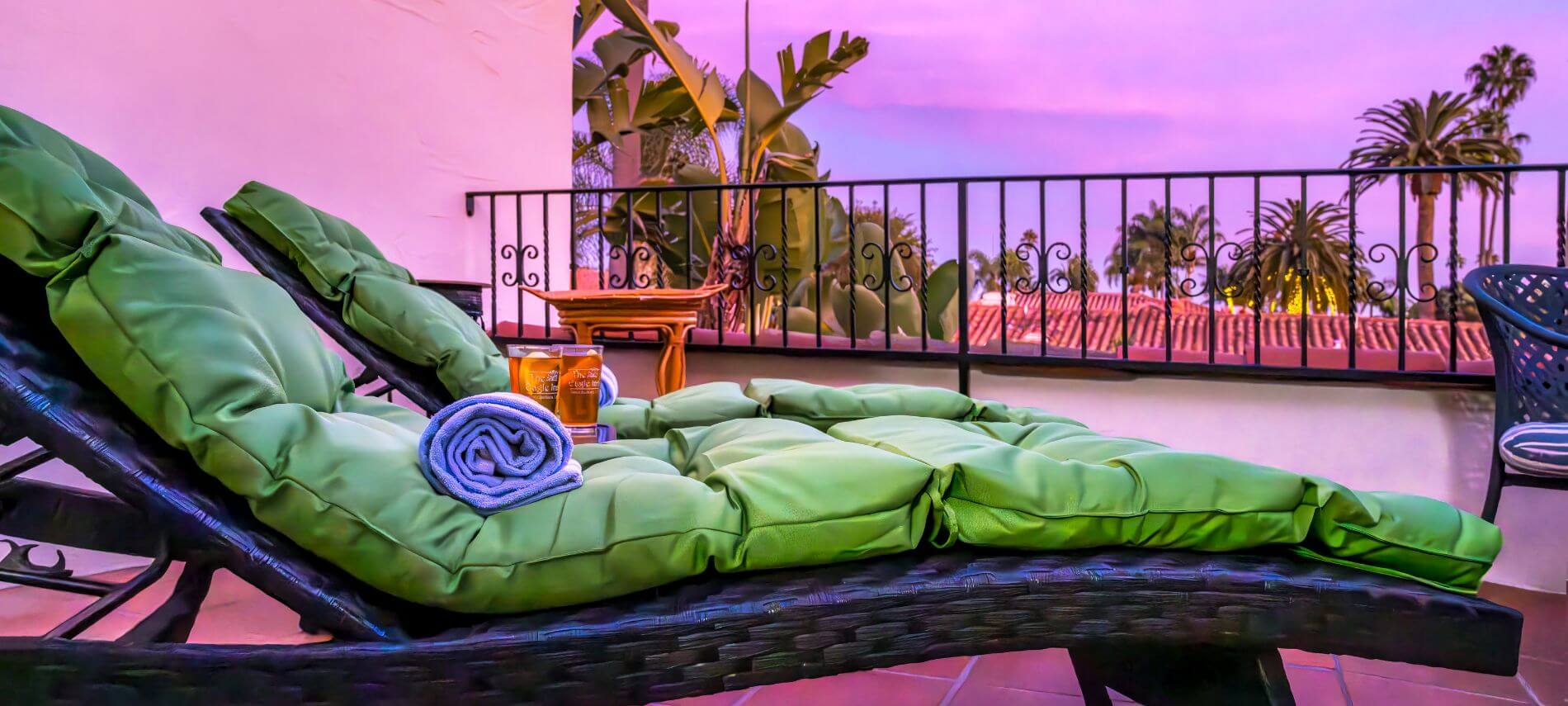 view across green cushioned lawn chairs at sunset, stand holding 2 glasses of tea