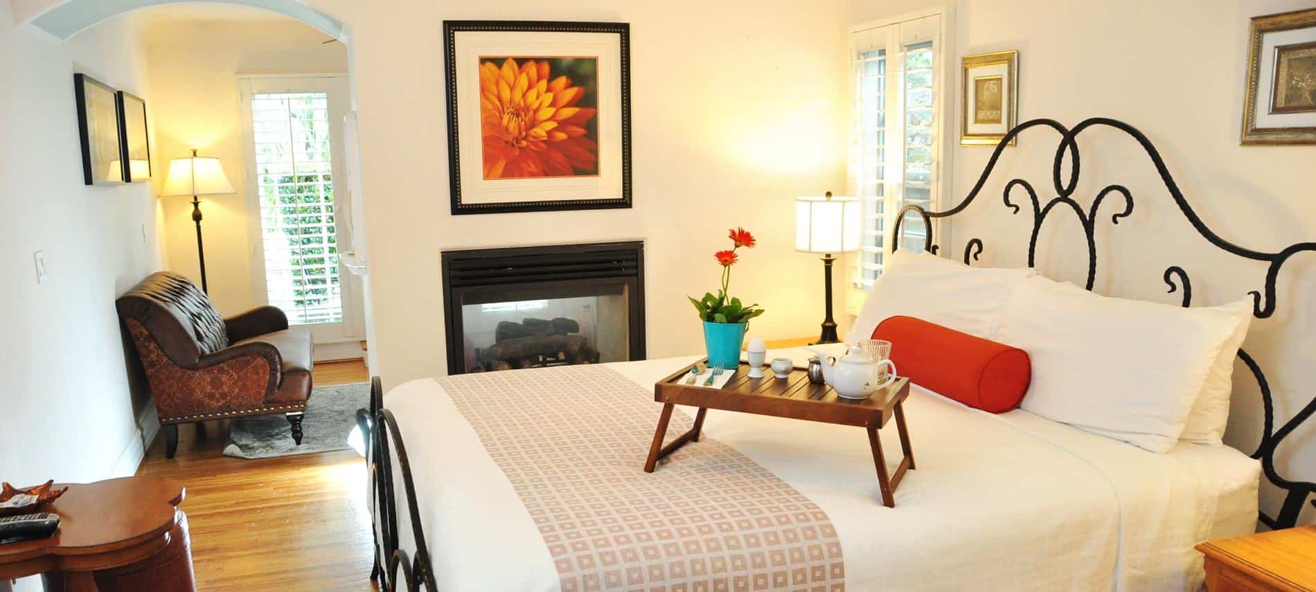 Beautiful San Clemente guest room with iron bed, white bedding, white walls and wood floors