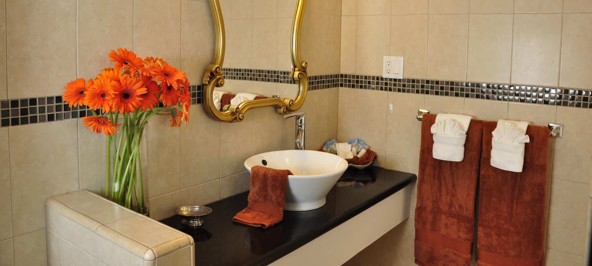 Santa Catalina guest bath with black vanity top, white vessel bowl sink, and gold mirror