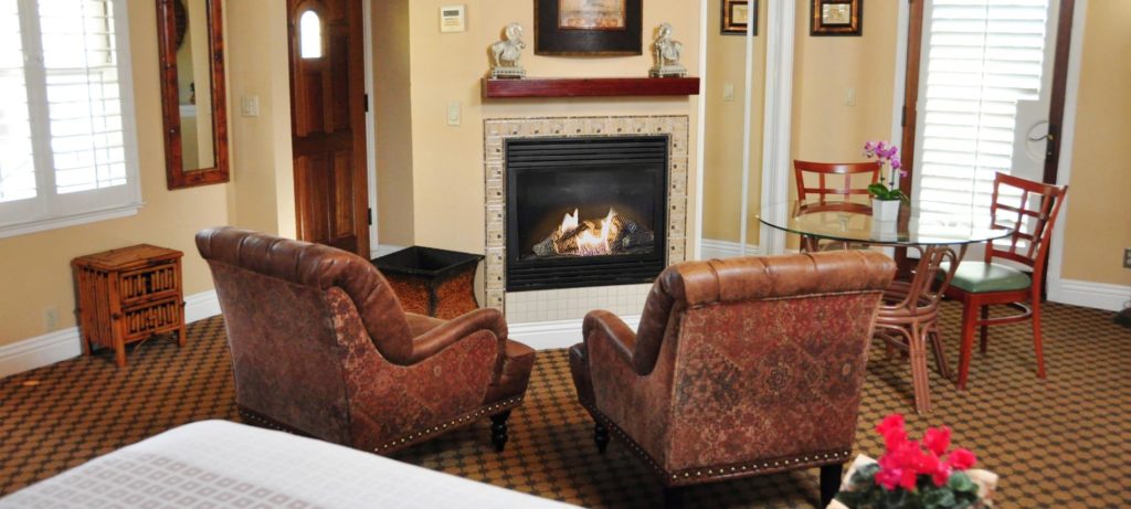 Spacious Santa Rosa guest room with fireplace, two leather chairs, and carpeting