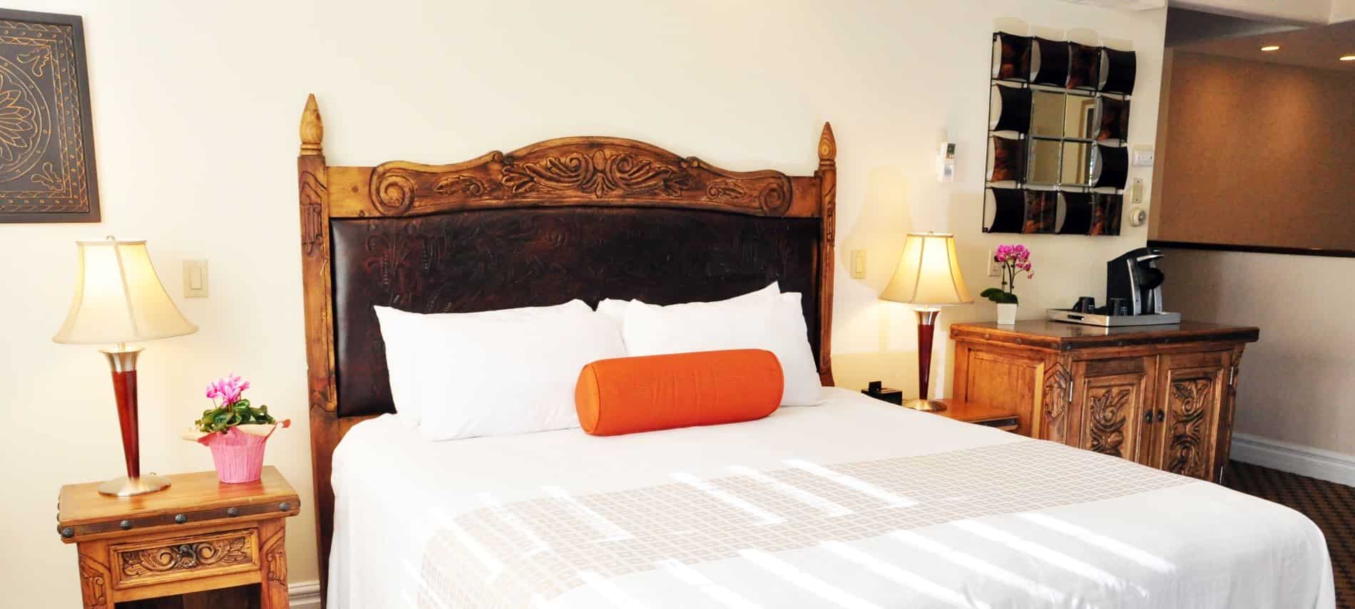 Superior King guest room with wood and leather headboard, wood furniture, coffee maker, and fresh flowers