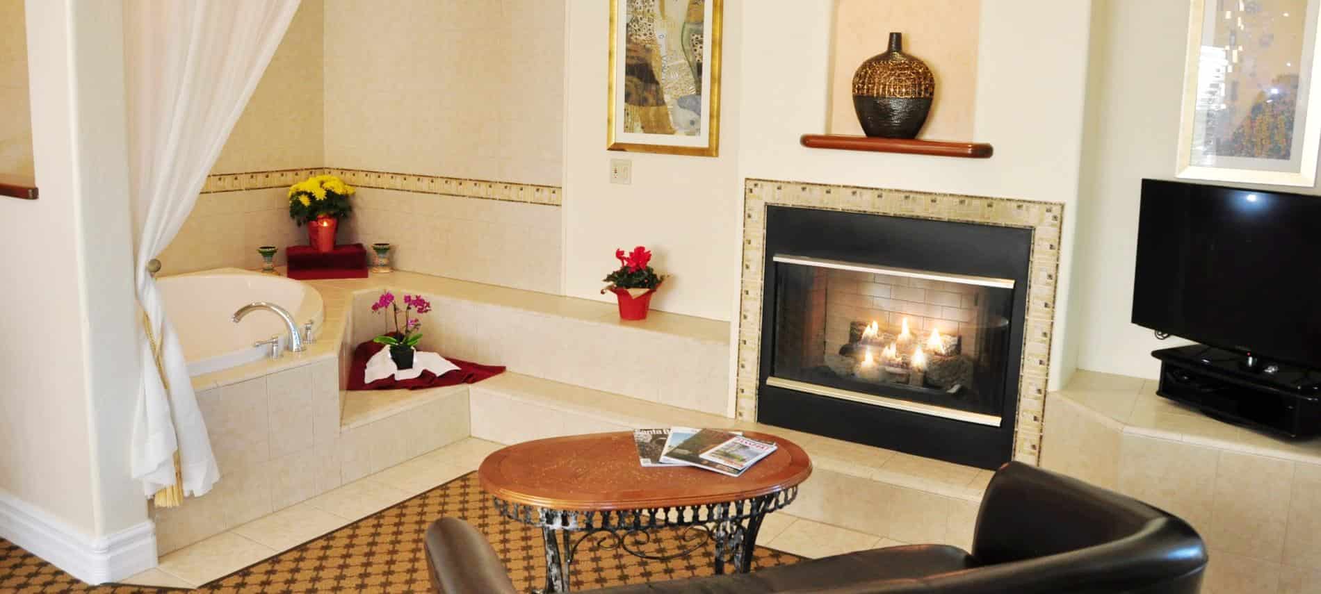 Superior King guest room with two person tub, fireplace, and TV next to coffee table and leather loveseat