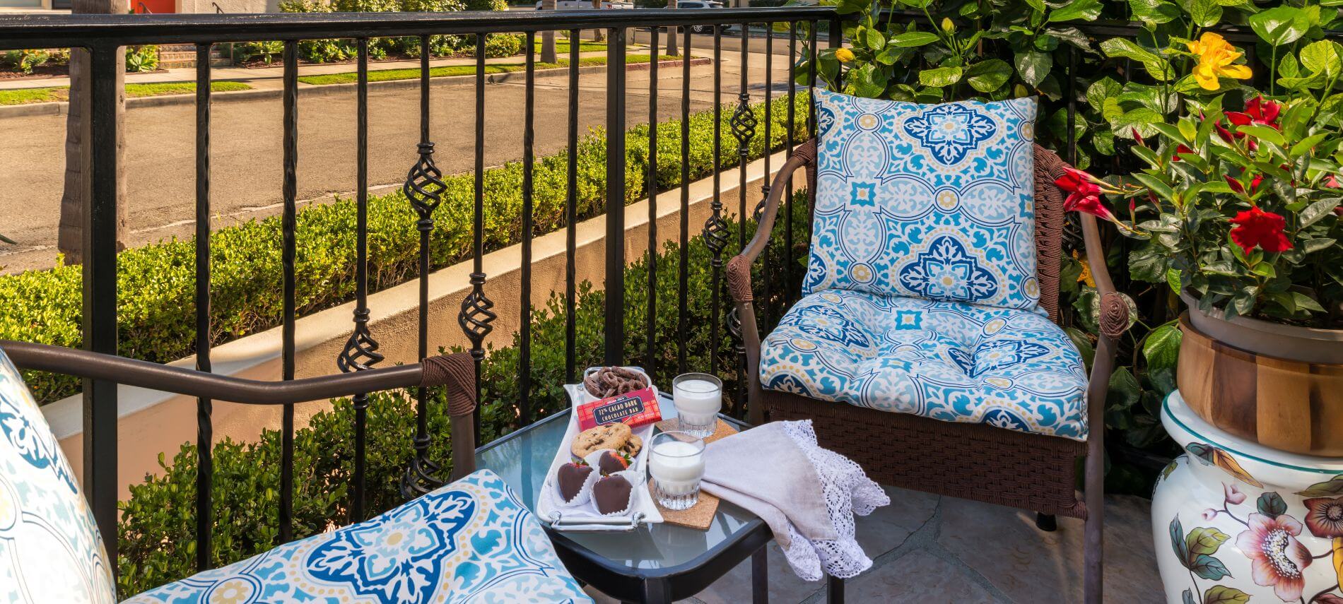 private patio by street, blue cushioned wicker chairs, small square glass table with refreshements