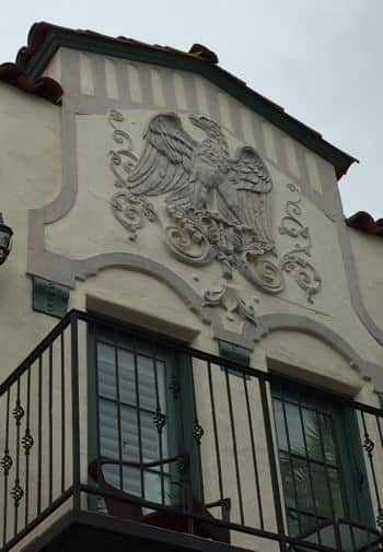 Close up view of The Eagle Inn's stucco building with engraved Eagle and balcony with black metal railing