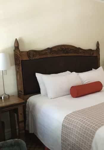 King guest room with wood and leather headboard and white linens