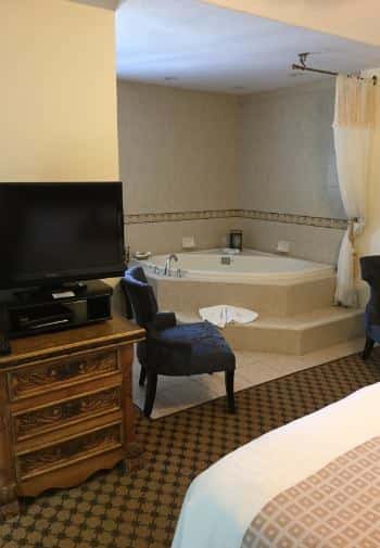 Deluxe king guest room with TV on wooden dresser and whirlpool tub