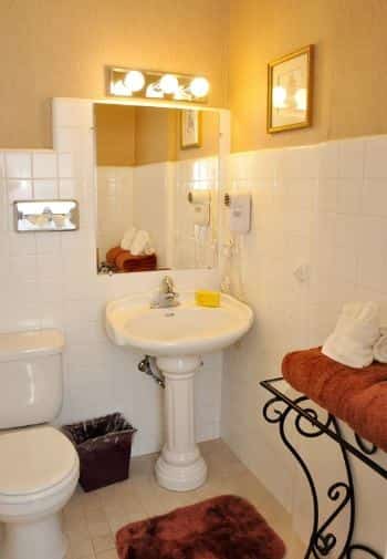 Queen balcony guest room bathroom with white pedestal sink and white tile on walls