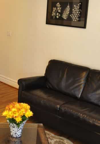 San Clemente guest room with leather couch and coffee table with yellow flowers