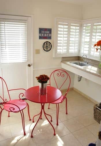 San Miguel guest room with tiled floor, half-light door, small red dinette for two, corner window and counter with sink