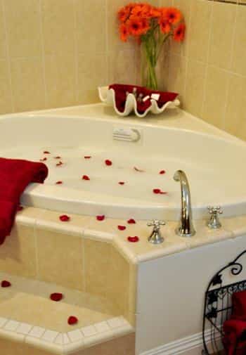 San Miguel guest bath corner tub with tiled walls and steps topped with red rose petals