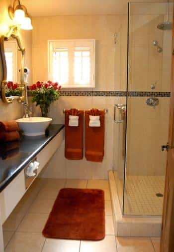 San Nicolas guest bath, small window, long black vanity top with white vessel bowl sink and tiled shower with glass door