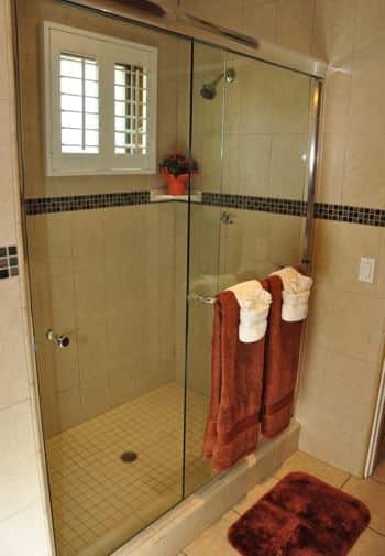 Santa Catalina guest bath with tiled walk-in shower, small window, and glass shower door