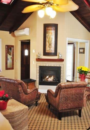 Santa Rosa guest room with vaulted wood ceilings, corner fireplace, two leather chairs, carpeting and ceiling fan