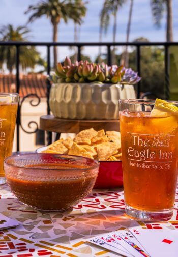 two glasses with the eagle inn logo filled with iced tea, chips and salsa in bowls sitting on table at dusk